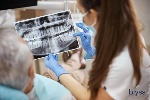 female dentist holding a dental x-ray image of teeth and showing it to her elderly patient