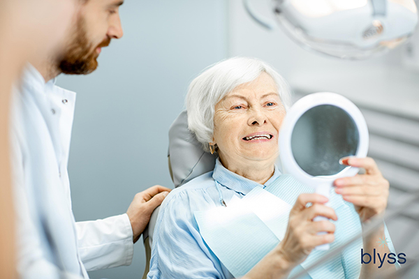 elderly woman looking at the mirror enjoying her smile in the dental office