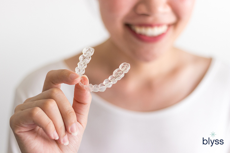 female right hand holding invisalign clear aligners